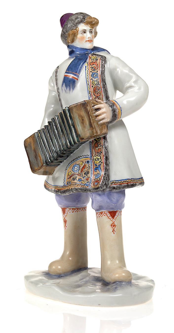 A Soviet Porcelain Figurine of a Peasant Musician with a Harmonica