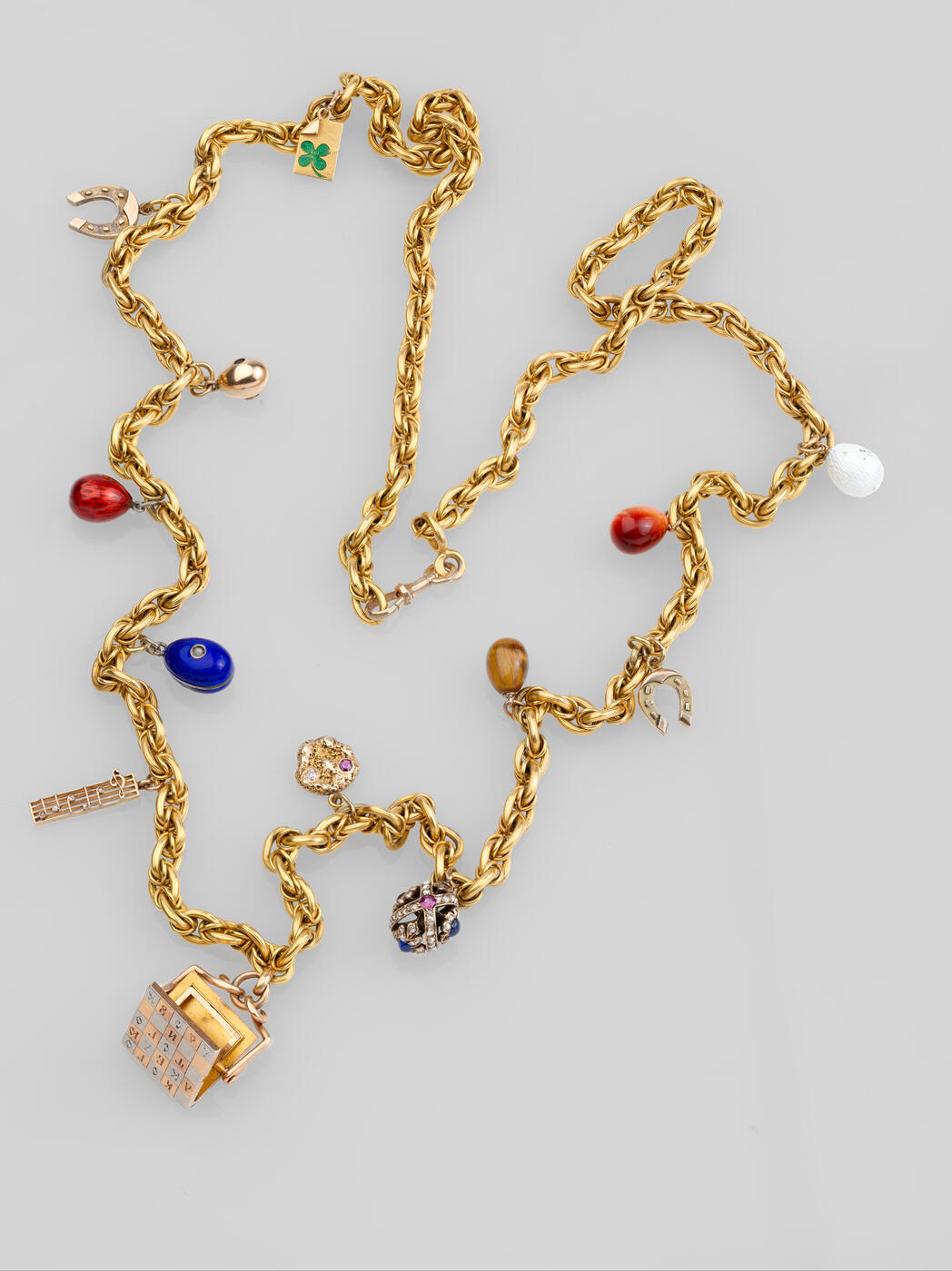 Thirteen Charms including a Fabergé Egg Pendant and a Commemorative Photograph Frame on Gold Chain